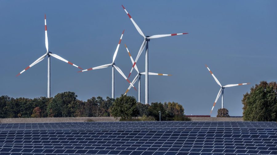 Wind turbines turn behind a solar farm in Rapshagen, Germany, Oct. 28, 2021. Germany has called for governments around the world to work on setting an ambitious target for renewable energy that would "ring in the end of the fossil fuel age" and help prevent dangerous global warming. Germany welcomed a deal Friday, June 16, 2023 among European Union countries to increase by more than a third the bloc’s renewable energy target for 2030. (AP Photo/Michael Sohn, File)