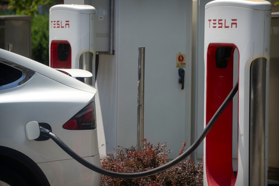 A vehicle charges at an electric vehicle charging station outside of a Tesla dealership in Beijing, Saturday, June 24, 2023. Threatened by possible shortages of lithium for electric car batteries, automakers are racing to lock in supplies of the once-obscure "white gold" in a politically and environmentally fraught competition from China to Nevada to Chile. (AP Photo/Mark Schiefelbein)