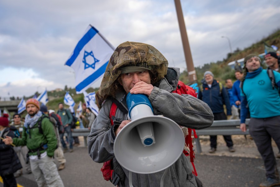 FILE - Israeli military reservists protest against the plans by Prime Minister Benjamin Netanyahu's government to overhaul the judicial system, on a freeway from Tel Aviv to Jerusalem, on Feb. 9, 2023. Dozens of reservists from the Israeli Air Force have released a letter renewing threats to refuse to show up for duty if the government moves ahead with a contentious plan to overhaul the country's judiciary. (AP Photo/Ohad Zwigenberg, File)