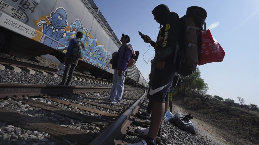 FILE - Migrants watch a train go past as they wait along the train tracks hoping to board a freight train heading north, one that stops long enough so they can hop on, in Huehuetoca, Mexico, May 12, 2023, the day after U.S. pandemic-related asylum restrictions called Title 42 were lifted. Unwittingly, migrants in Latin America finance disinformation during their journeys to the U.S., as they fall victim to fraud that can cost them thousands of dollars and that in turn has served to develop new business models, from fake work recruiters to those who call themselves "migration coaches." (AP Photo/Marco Ugarte, File)