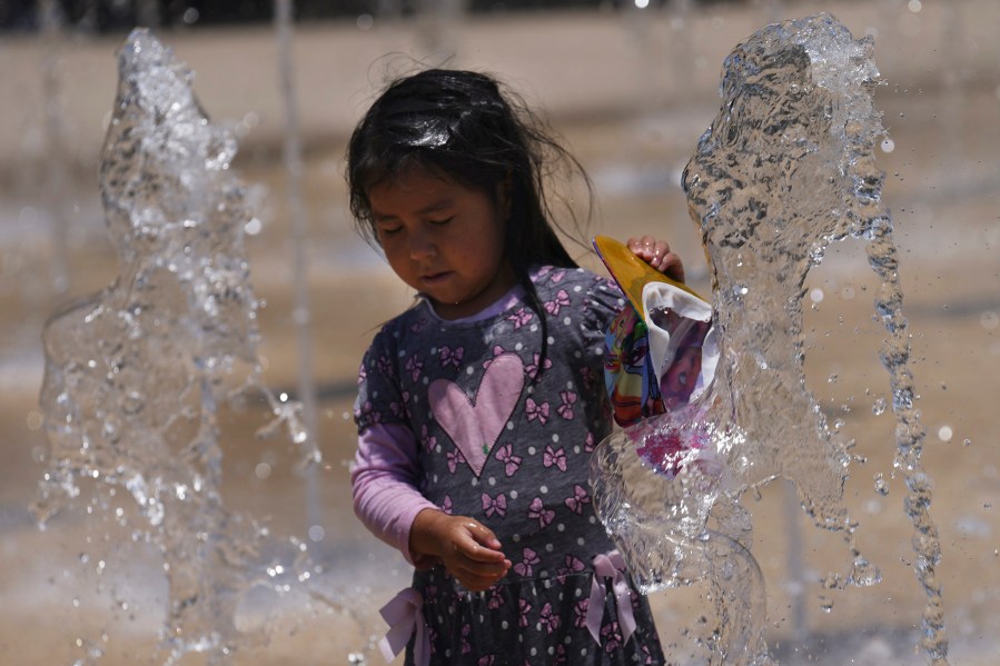 A girl plays in the water of a decorative fountain at Revolution Monument on a hot day in Mexico City, Tuesday, June 13, 2023. (AP Photo/Marco Ugarte)