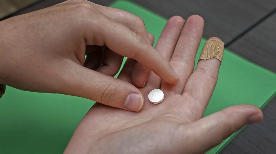 A patient prepares to take the first of two combination pills, mifepristone, for a medication abortion during a visit to a clinic.