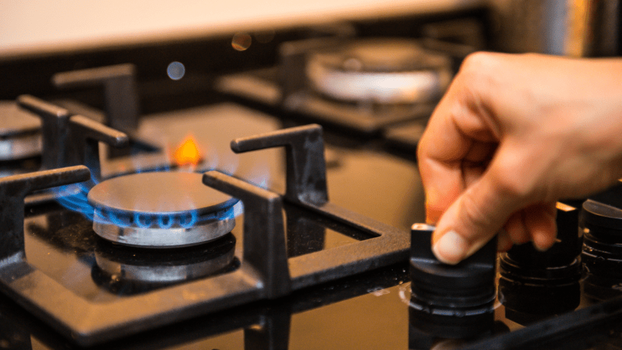 A person is seen starting a burner on a gas stove in a closeup/