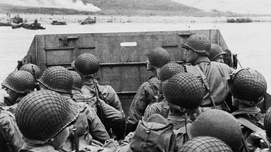 American assault soldiers in a landing craft huddle behind a shield in this historical photo from D-Day.