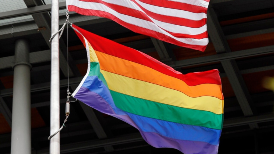 A gay pride flag flutters with the American flag.