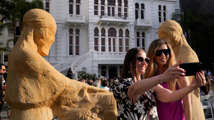 Two guests take selfie in front of two sculptures in the courtyard of the Sursock Museum during an opening event for the iconic venue in Beirut, Lebanon, Friday, May 26, 2023. The museum has reopened to the public, three years after after a deadly explosion in the nearby Beirut port reduced many of its treasured paintings and collections to ashes. (AP Photo/Hussein Malla)