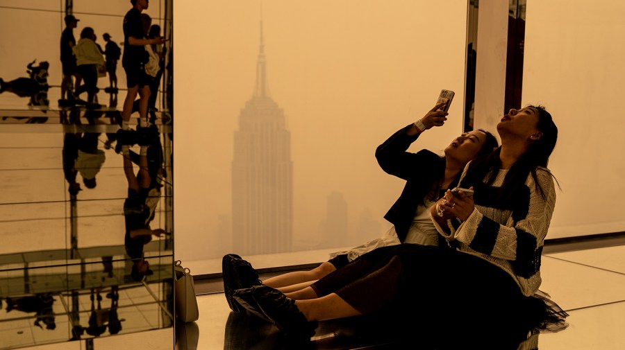 Visitors at Summit One Vanderbilt look out at a smoke-shrouded Manhattan