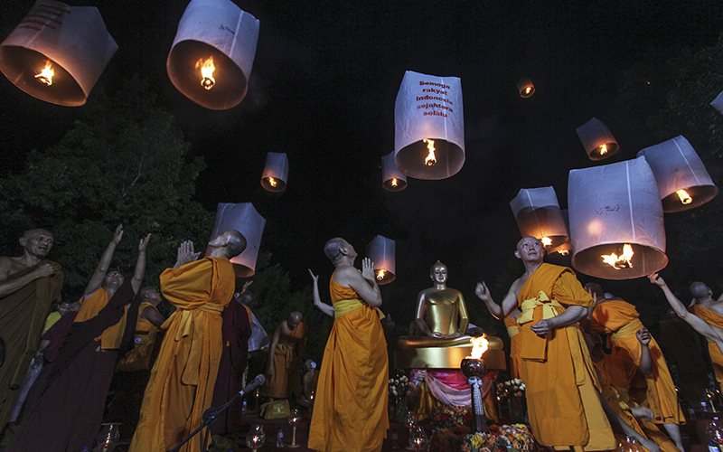 Buddhist monks release lanterns into the night sky during a Vesak Day procession