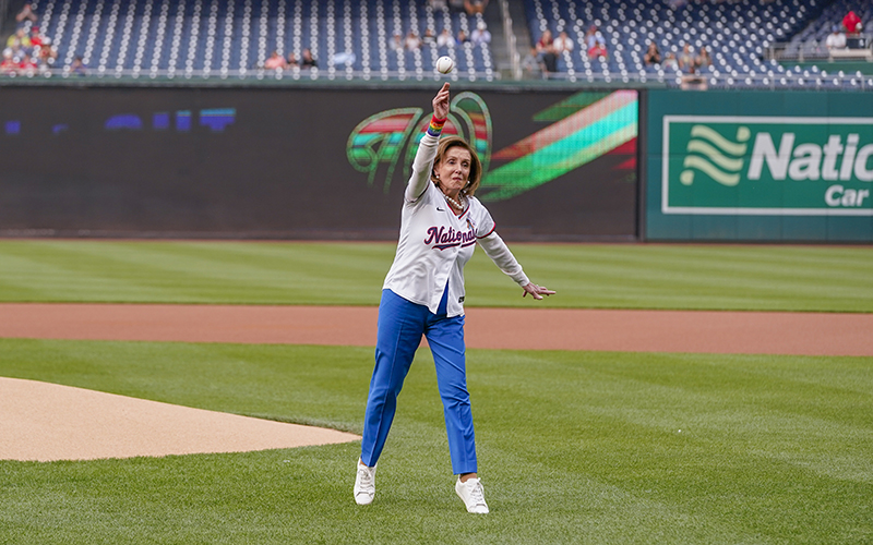 Rep. Nancy Pelosi (D-Calif.) stands in the middle of a baseball field as she throws out a ceremonial first pitch