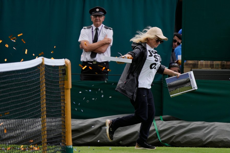 A Just Stop Oil protester runs onto Court 18 and releases confetti on day three of the Wimbledon tennis championships in London, Wednesday, July 5, 2023. (AP Photo/Alastair Grant)