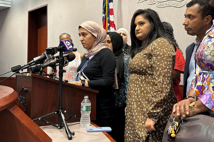 CORRECTS SPELLING OF FIRST NAME TO MARYAM, NOT MAYRAM - Connecticut state legislator Rep. Maryam Khan, left, with her right arm in a sling and surrounded by friends, family and fellow lawmakers, in Hartford, Conn., Thursday July 6, 2023, gives a harrowing account of her attack last month as she left a Muslim prayer service. (AP Photo/Susan Haigh)