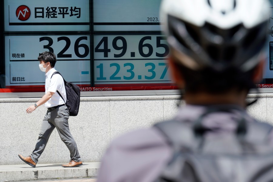 A person walks in front of an electronic stock board showing Japan's Nikkei 225 index at a securities firm Friday, July 7, 2023, in Tokyo. Asian shares slipped Friday after another decline on Wall Street, where hopes for an end to interest rate hikes have been dashed by strong economic data. (AP Photo/Eugene Hoshiko)