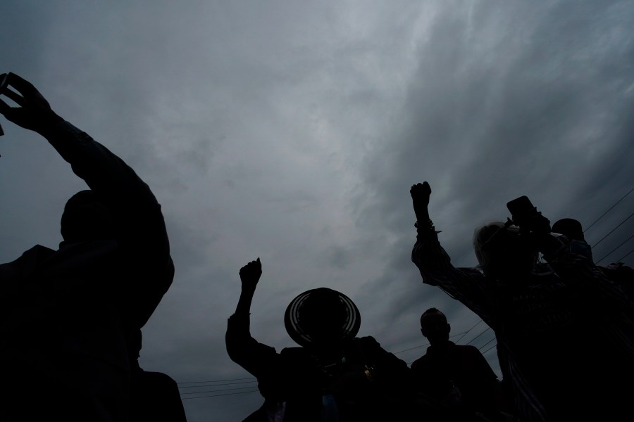 FILE - People raise up their arms during the dedication of a prayer wall outside of the historic Vernon African Methodist Episcopal Church in the Greenwood neighborhood during the centennial of the Tulsa Race Massacre, May 31, 2021, in Tulsa, Okla. An Oklahoma judge has thrown out a lawsuit seeking reparations for the 1921 Tulsa Race Massacre, dashing an effort to obtain some measure of legal justice by survivors of the deadly racist rampage. (AP Photo/John Locher, file)