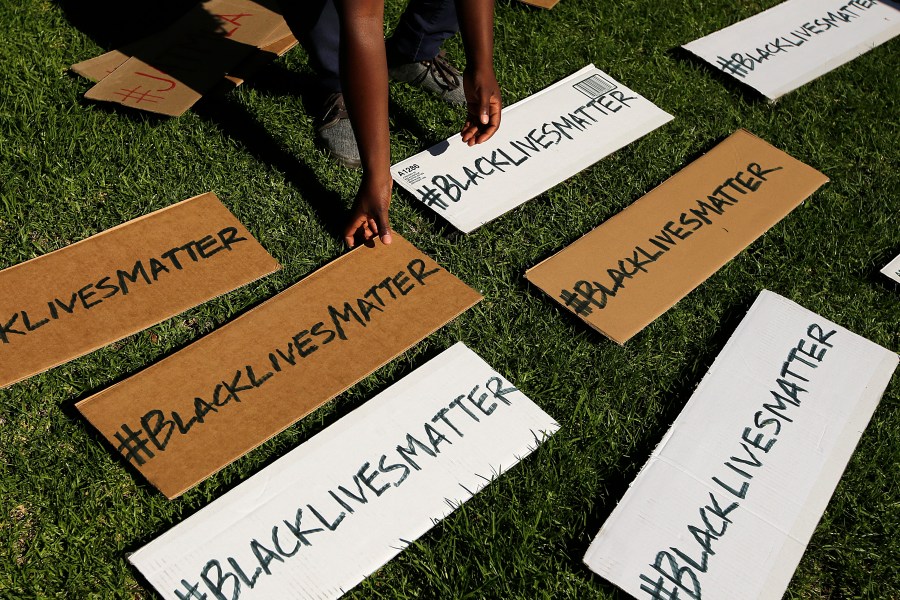 FILE - A protester picks up signs during a demonstration in Beverly Hills, Calif., July 17, 2013, in reaction to the acquittal of neighborhood watch volunteer George Zimmerman in the 2012 death of Trayvon Martin. The Black Lives Matter movement hits a milestone on Thursday, July 13, 2023, marking 10 years since its 2013 founding in response to Zimmerman's acquittal. (AP Photo/Jae C. Hong, File)