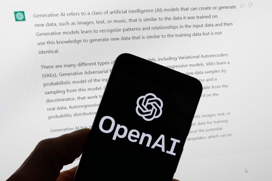 FILE - The OpenAI logo is seen on a mobile phone in front of a computer screen displaying output from ChatGPT, March 21, 2023, in Boston. The U.S. Federal Trade Commission has launched an investigation into ChatGPT creator OpenAI and whether the artificial intelligence company violated consumer protection laws by scraping public data and publishing false information through its chatbot, according to reports in the Washington Post and the New York Times. (AP Photo/Michael Dwyer, File)