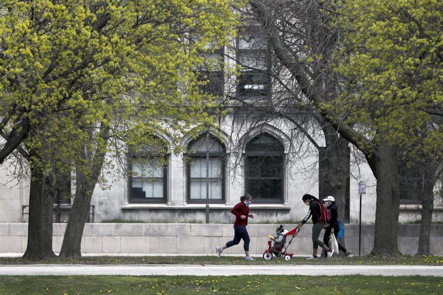 File - Pedestrians pass near the University of Chicago Monday, April 27, 2020, in Chicago. Anonymous comments with racist, sexist and abusive messages that were posted for years on a jobs-related website for economists originated from numerous leading U.S. universities, including Harvard, Stanford, and the University of Chicago, according to research released Thursday. (AP Photo/Charles Rex Arbogast, File)