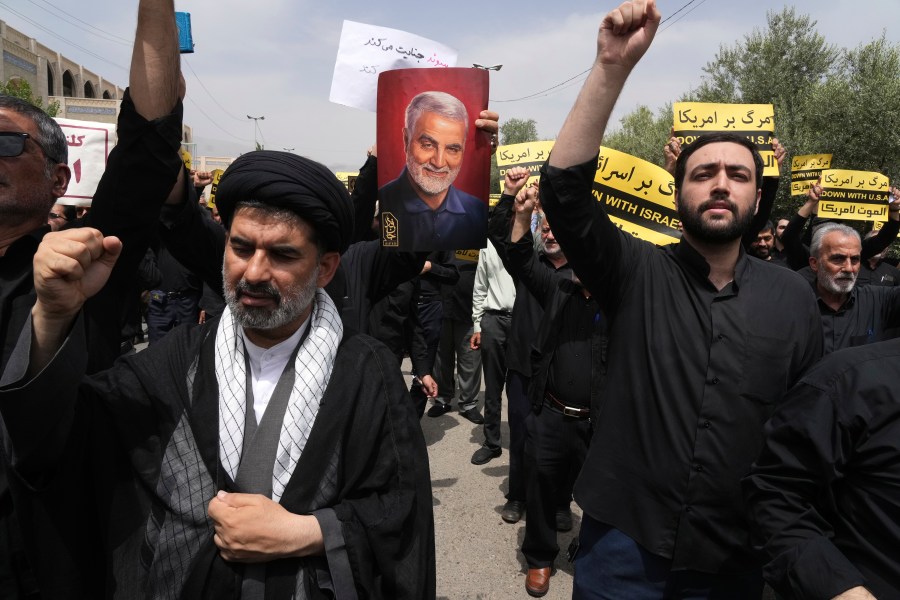 Iranian worshippers chant slogans as one of them holds a poster of the late Revolutionary Guard Gen. Qassem Soleimani, who was killed in a U.S. drone attack in 2020, in a protest against Sweden after the Nordic nation allowed an Iraqi man insult the Muslim holy book, the Quran, after their Friday prayers in Tehran, Iran, Friday, July 21, 2023. (AP Photo/Vahid Salemi)