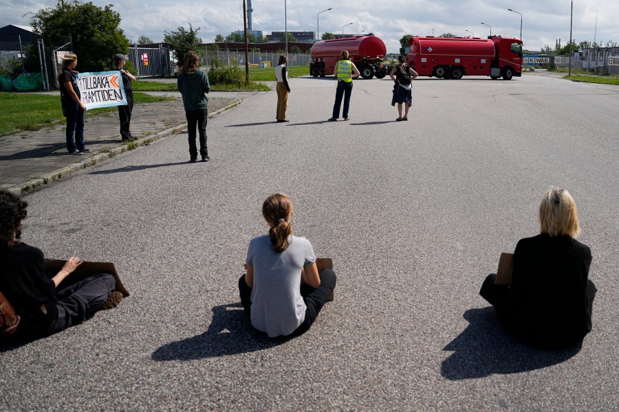 A truck turns back as Greta Thunberg, center, and other activists block the entrance to an oil facility in Malmo, Sweden, Monday, July 24, 2023. The protest took place just a few hours after Thunberg was fined for disobeying police during a similar protest last month at the same terminal. (AP Photo/Pavel Golovkin)