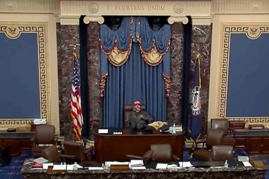 This image from U.S. Senate video, introduced at the trial of Bruno Joseph Cua, shows Cua sitting with his feet up in the Senate chamber on Jan. 6, 2021, during the riot at the U.S. Capitol. Cua, who stormed the U.S. Capitol, assaulted a police officer and sat in a Senate floor chair reserved for the vice president was sentenced on Wednesday, July 26, 2023, to one year in prison.(Senate Television via AP)