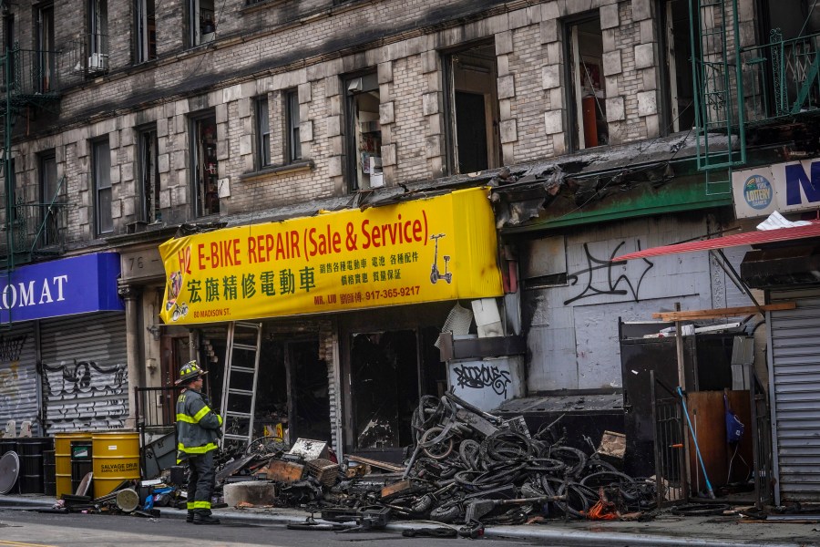 FILE - A firefighter looks through debris in the aftermath of a fire which authorities say started at an e-bike shop and spread to upper-floor apartments, Tuesday June 20, 2023, in New York. Federal officials are looking into cracking down on defective lithium-ion batteries that power hoverboards, scooters and motorized bicycles because of a rash of deadly fires caused by exploding batteries. The effort comes as New York City implements new laws meant to reduce the number of fires, injuries and deaths in a city where e-bikes have become ubiquitous.(AP Photo/Bebeto Matthews, File)