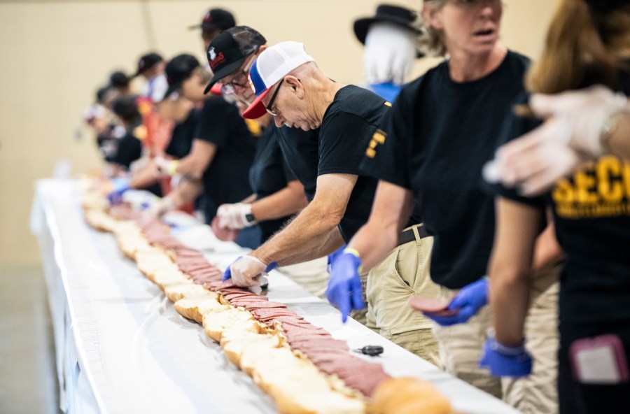 Volunteers assemble a 150-foot-long (45.7-meters-long) bologna sandwich at the Lebanon Area Fair on Tuesday, July 25, 2023 in Lebanon, Pa. Every footlong “bite” was sponsored at $100 per foot. The money was donated to Lebanon County Christian Ministries and their efforts to help people dealing with food insecurity in the Lebanon Valley. (Sean Simmers/The Patriot-News via AP)