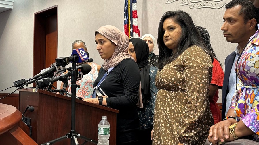 Connecticut state legislator Rep. Maryam Khan, left, with her right arm in a sling and surrounded by friends, family and fellow lawmakers, in Hartford, Conn., Thursday July 6, 2023, gives a harrowing account of her attack last month as she left a Muslim prayer service. (AP Photo/Susan Haigh)