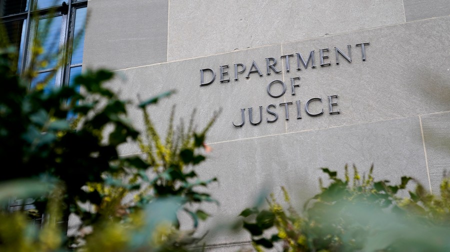 A sign for the Department of Justice is seen on the side of a building.