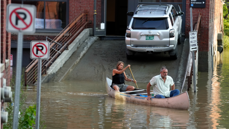 Jodi Kelly, left, practice manager at Stonecliff Veterinary Surgical Center, behind, and her husband, veterinarian Dan Kelly, use a canoe to remove surgical supplies from the flood-damaged center, Tuesday, July 11, 2023, in Montpelier, Vt. The supplies included orthopedic implants for an upcoming surgery on a dog. (AP Photo/Steven Senne)