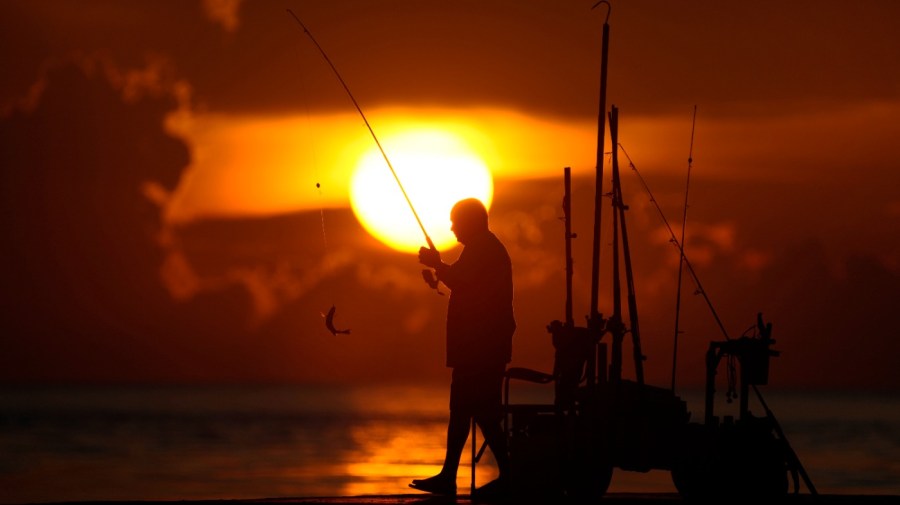 A fisherman reels in his catch as the sun rises over the Atlantic Ocean, June 28, 2023, in Bal Harbour, Fla. An already warming Earth steamed to its hottest June on record, with global oceans setting temperature records for the third straight month, the U.S. National Oceanic and Atmospheric Administration announced Thursday, July 13. (AP Photo/Wilfredo Lee, File)