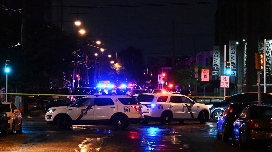 Police cars with lights on block a street at night.