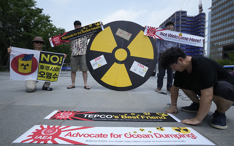 Environmental activists display banners that show nuclear waste symbols and read "NO!" "Not Welcome Here!" "Advocate for the Nuclear Industry" and "Advocate for Ocean Dumping" to protest Japan's decision to release treated radioactive water in Seoul