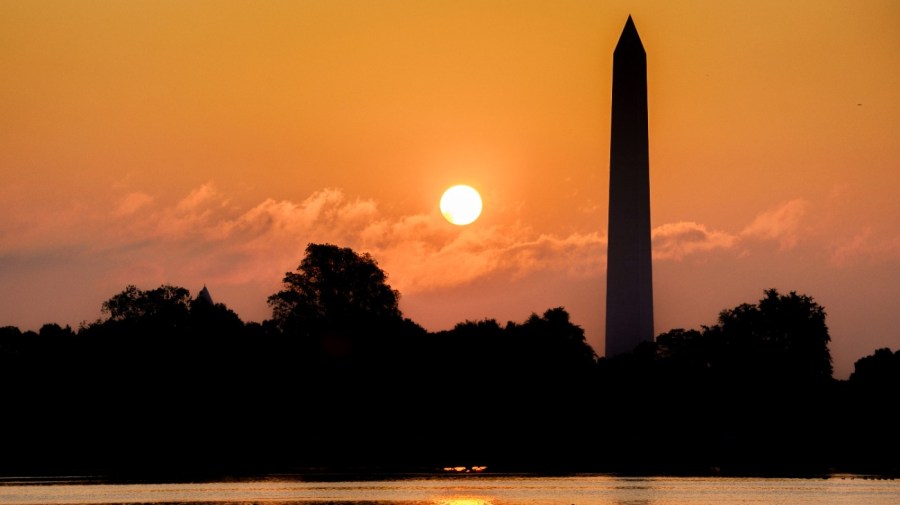 A rowing team glides along the Potomac River past the Washington Monument as the sun rises on another hot and humid day in Washington, Thursday, July 20, 2023. (AP Photo/J. David Ake)