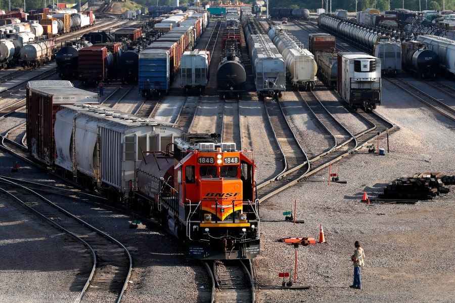 FILE- A BNSF rail terminal worker monitors the departure of a freight train, on June 15, 2021, in Galesburg, Ill. Roughly 7,500 BNSF train engineers will soon get up to eight days of paid sick time and more predictable schedules if they approve a deal with the railroad that was announced Tuesday, Aug. 1, 2023. (AP Photo/Shafkat Anowar, File)