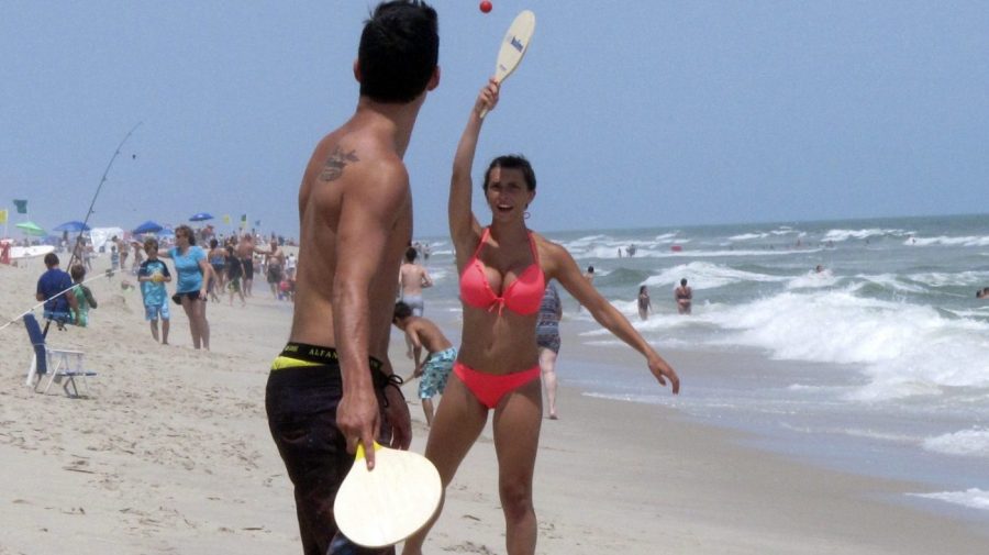 Beachgoers play paddle ball on the beach in Ship Bottom, N.J. on June 30, 2014. On Aug. 4, 2023, a German wind power company and a New York utility applied for permission to build a wind farm 37 miles off the coast of Long Beach Island, far enough out to sea that it could not be seen from the beach. (AP Photo/Wayne Parry)