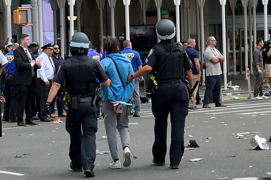 New York Police escort a man who was arrested in Union Square, Friday, Aug. 4, 2023, in New York. Police in New York City are struggling to control a crowd of thousands of people who gathered in Manhattan's Union Square for an Internet personality's videogame console giveaway that got out of hand. (AP Photo/Bobby Calvan)