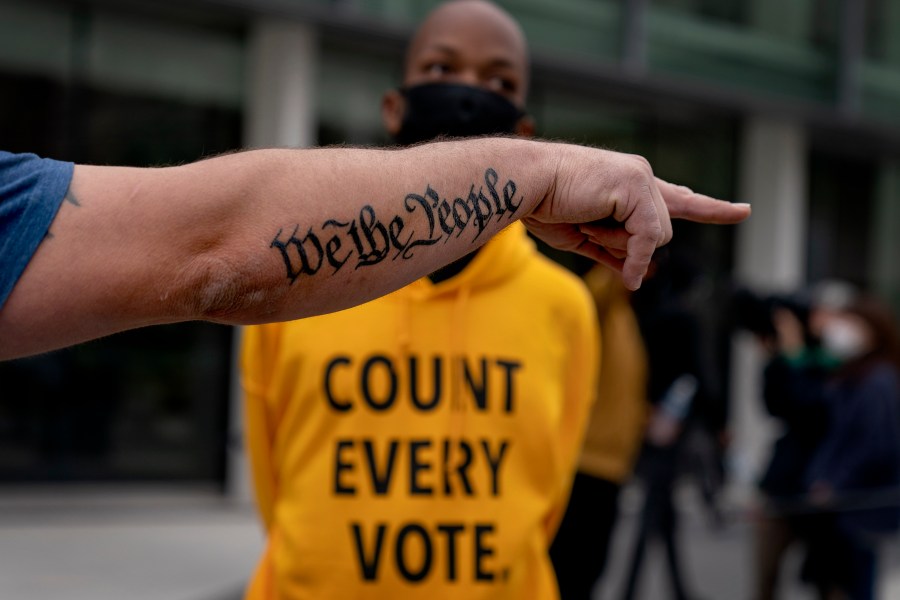 FILE - The tattoo "We The People", a phrase from the United States Constitution, decorates the arm of President Donald Trump supporter Bob Lewis, left, as he argues with counter protestor Ralph Gaines while Trump supporters demonstrate against the election results outside the central counting board at the tcf Center in Detroit, Nov. 5, 2020. (AP Photo/David Goldman, File)