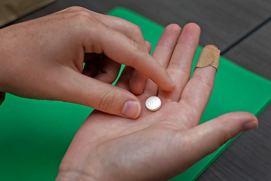 FILE - A patient prepares to take the first of two combination pills, mifepristone, for a medication abortion during a visit to a clinic in Kansas City, Kan., on, Oct. 12, 2022. New restrictions on access to the drug used in the most common form of abortion would be imposed under a federal appeals court ruling issued Wednesday, Aug. 16, 2023, but the Supreme Court will have the final say. (AP Photo/Charlie Riedel, File)