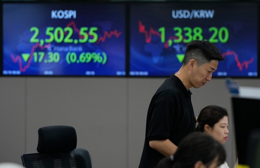 A currency trader watches monitors near the screens showing the Korea Composite Stock Price Index (KOSPI), top left, and the foreign exchange rate between U.S. dollar and South Korean won at the foreign exchange dealing room of the KEB Hana Bank headquarters in Seoul, South Korea, Friday, Aug. 18, 2023. (AP Photo/Ahn Young-joon)