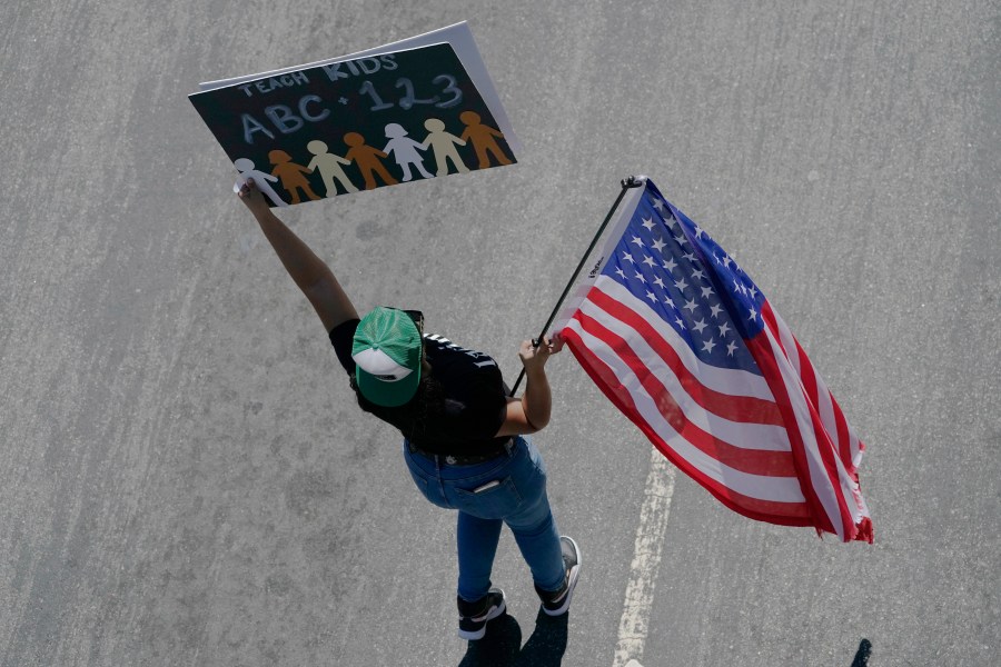 A demonstrator with the Leave our Children Alone holds a sign during a Parents Rights group march on Third St., downtown to Los Angeles Unified School District headquarters on Tuesday, Aug. 22, 2023. (AP Photo/Damian Dovarganes)