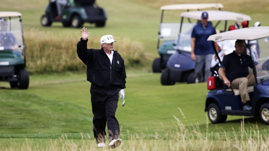 Then-President Trump waves to protesters while playing golf at a club in Scotland.