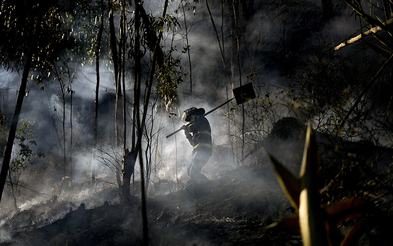 A firefighter walks through the smoke of a mountain fire in Soacha near Bogota, Colombia