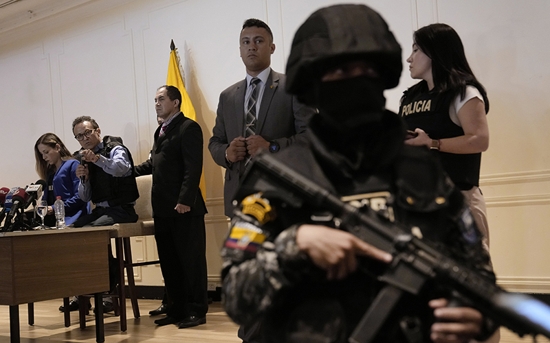 Wearing a bulletproof vest, Christian Zurita, second from left, who replaces slain presidential candidate Fernando Villavencencio, gives a press conference. An armed guard stands close to the camera on the right