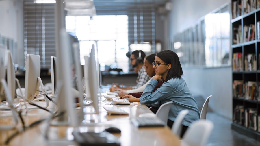 University students work computers in a campus library.