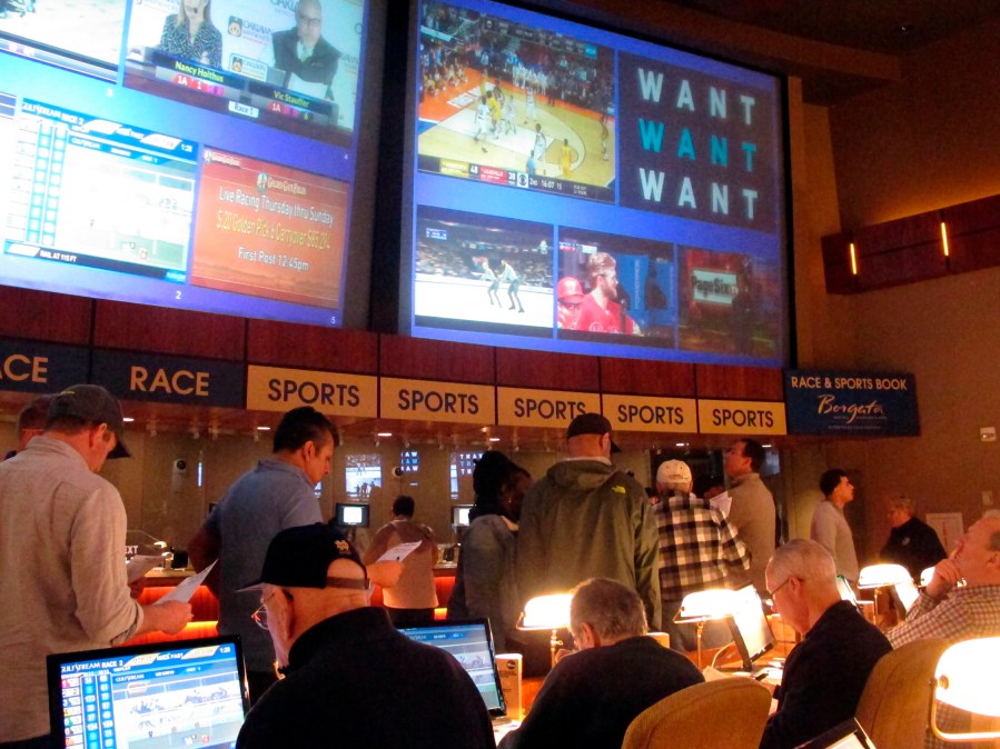 FILE - Gamblers line up to place bets on the NCAA men's college basketball tournament at the Borgata casino in Atlantic City N.J., March 21, 2019. When the NFL season kicks off, Kentucky residents will be able to legally bet on games for the first time. When they do, they also will be funding the state's first-ever program for people with gambling problems. (AP Photo/Wayne Parry, File)