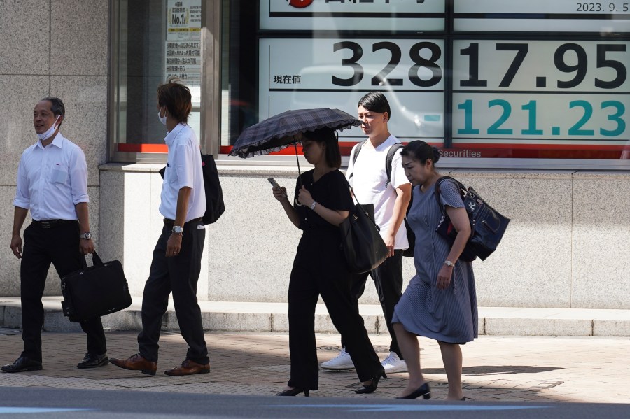 FILE - People walk in front of an electronic stock board showing Japan's Nikkei 225 index at a securities firm on Sept. 5, 2023, in Tokyo. Shares fell Friday, Sept. 8 in Asia after Japan reported its economy grew less than earlier estimated in the last quarter. (AP Photo/Eugene Hoshiko, File)