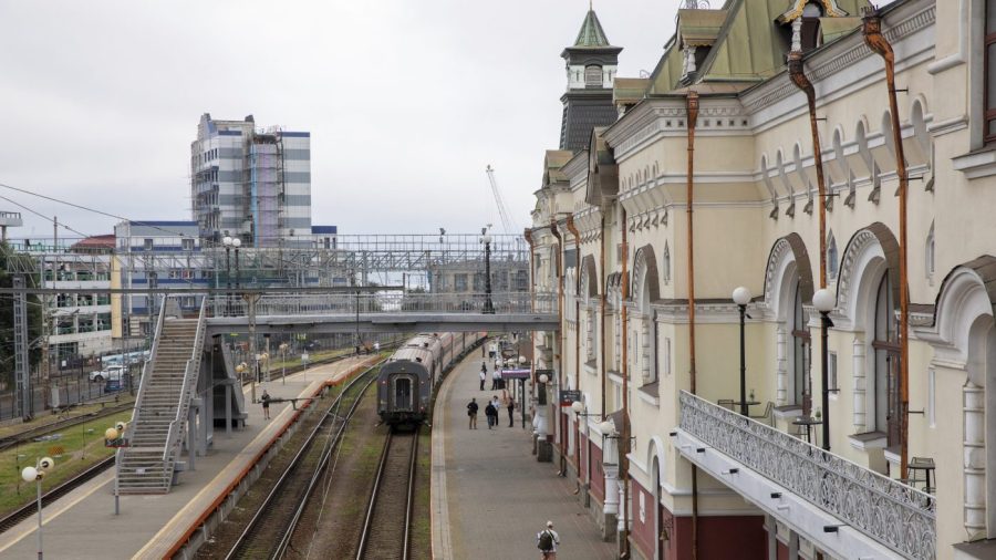 People walk alongside the main train station in Vladivostok, Russia.