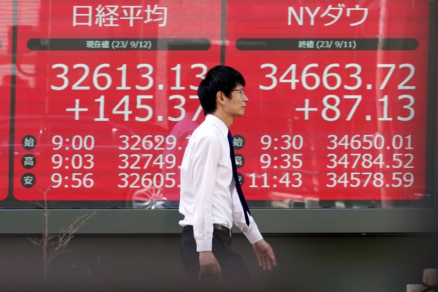 A person walks in front of an electronic stock board showing Japan's Nikkei 225 and New York Dow indexes at a securities firm Tuesday, Sept. 12, 2023, in Tokyo. Asian shares mostly declined Tuesday despite a Big Tech rally on Wall Street, as investors looked ahead to data on U.S. consumer prices set for later in the week. (AP Photo/Eugene Hoshiko)