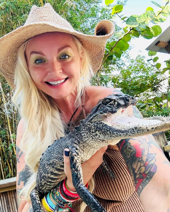 This photo posted on the Gatorland Facebook page on Saturday, Sept. 16, 2023 shows Savannah Boan, Crocodilian Enrichment Coordinator at the Gatorland theme park in Orlando, Fla., holding an alligator with a missing upper jaw that was that was rescued and brought to the park to be cared for. (Gatorland Facebook.com via AP)