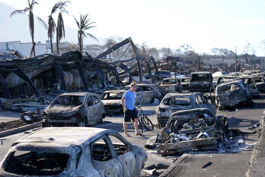 FILE - A man walks through wildfire wreckage Aug. 11, 2023, in Lahaina, Hawaii. The PGA Tour says Hawaii Gov. Josh Green has told them to "go forward" with plans to hold the season-opening Sentry Tournament of Champions at Kapalua on Jan. 4-7, 2024. (AP Photo/Rick Bowmer, File)