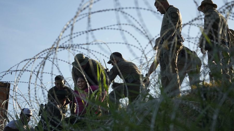 Migrants navigate around concertina wire along the banks of the Rio Grande after crossing from Mexico into the U.S., Tuesday, Aug. 1, 2023, in Eagle Pass, Texas.